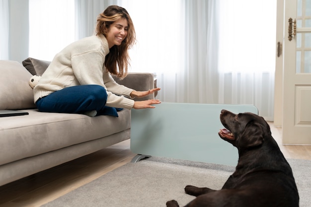 Mujer y perro sonrientes de tiro completo en casa