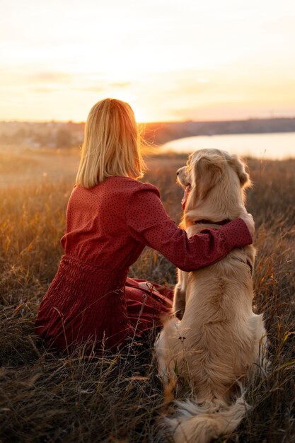 Mujer y perro de tiro completo al atardecer