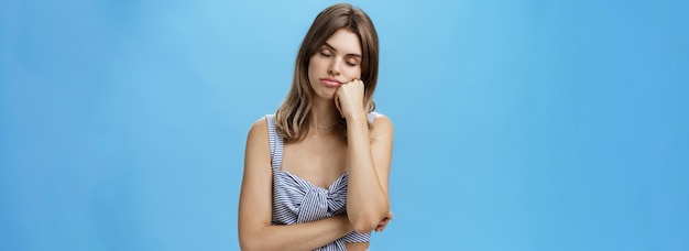 Mujer de pie aburrida y somnolienta tomando una siesta mientras escucha la conversación aburrida del jefe inclinando la cabeza sobre el puño