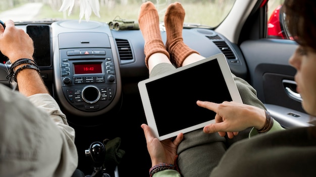 Mujer de pie en el asiento del pasajero con tableta cerca de novio