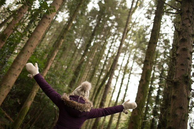 Mujer de pie en el bosque con los brazos abiertos