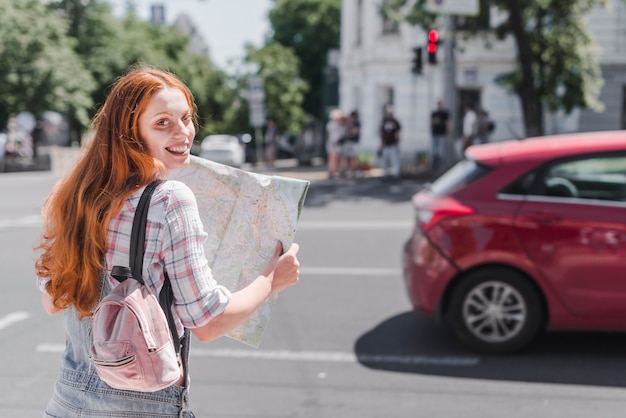 Mujer de pie en la calle con el mapa de la ciudad