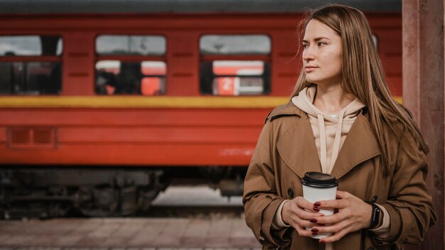 Mujer de pie delante de un tren en la estación de tren
