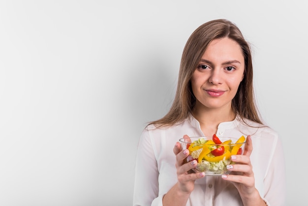 Mujer de pie con ensalada de verduras en un tazón pequeño