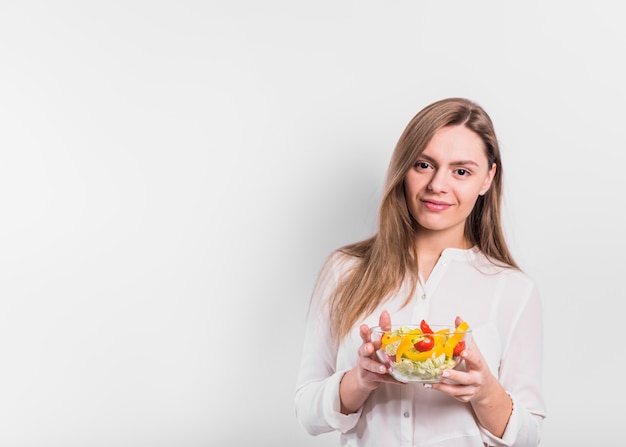 Mujer de pie con ensalada de verduras en un tazón