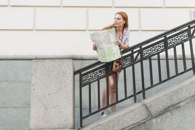 Mujer de pie en las escaleras con mapa de la ciudad