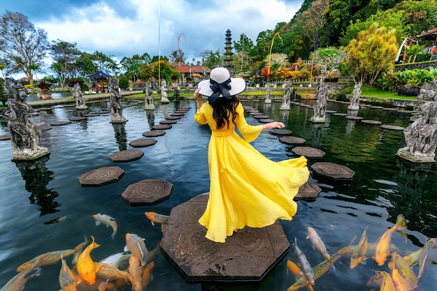 Mujer de pie en el estanque con peces de colores en Tirta Gangga Water Palace en Bali, Indonesia