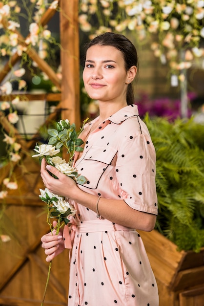 Foto gratuita mujer de pie con flores blancas en la mano