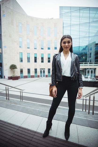 Foto gratuita mujer de pie fuera del edificio de oficinas