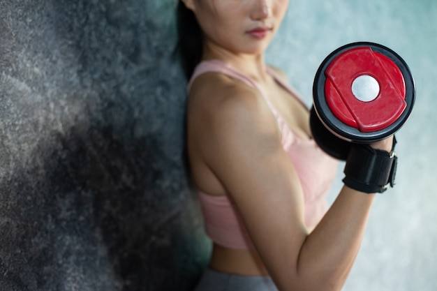 Mujer de pie haciendo ejercicio con una pesa roja en el gimnasio.