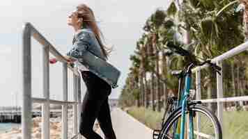 Foto gratuita mujer de pie junto a su bicicleta