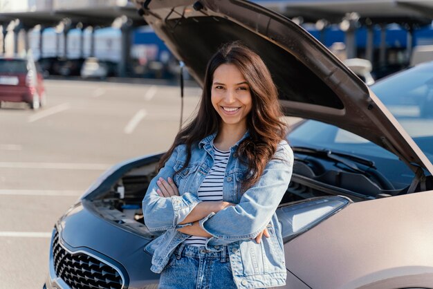 Mujer de pie junto a su coche roto