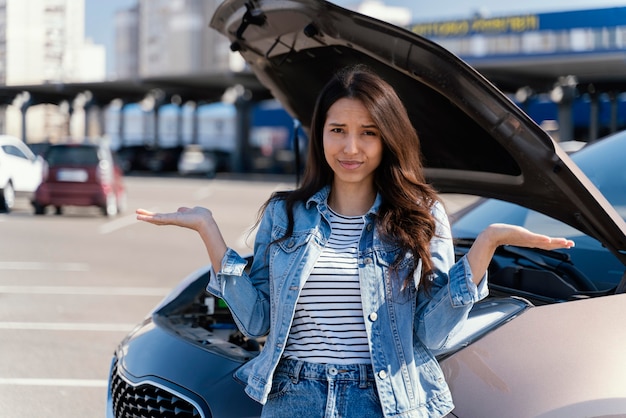 Mujer de pie junto a su coche roto