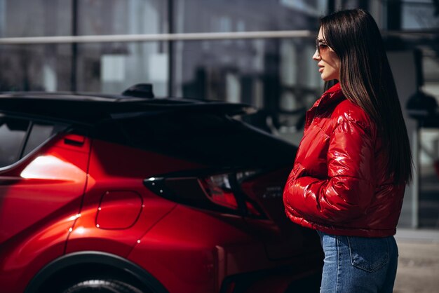 Mujer de pie junto a su nuevo coche rojo