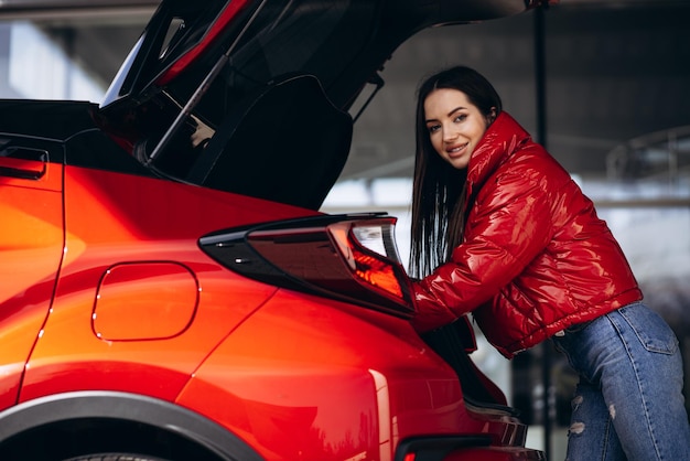 Mujer de pie junto a su nuevo coche rojo