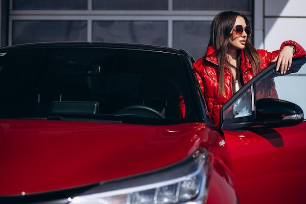 Mujer de pie junto a su nuevo coche rojo
