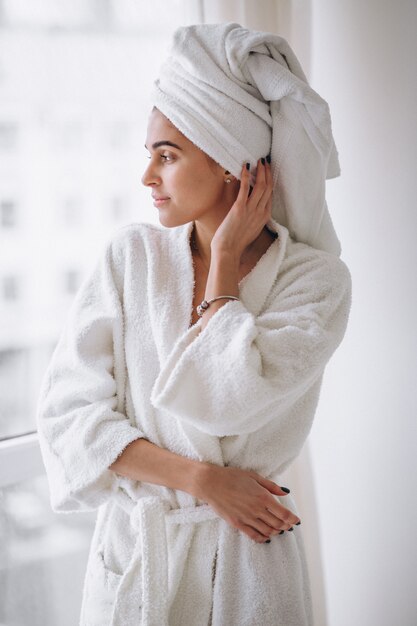 Mujer de pie junto a la ventana en bata de baño