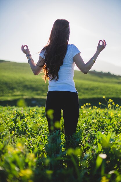 Mujer de pie y meditando en la hierba verde