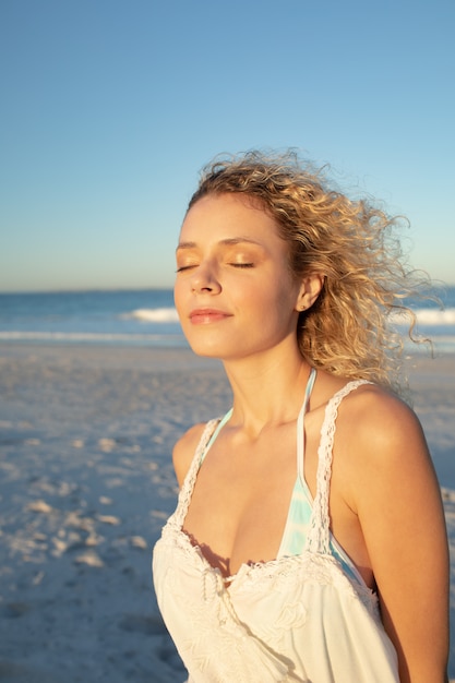 Mujer de pie con los ojos cerrados en la playa