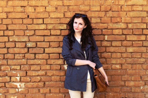 Mujer de pie con pared de ladrillos de fondo