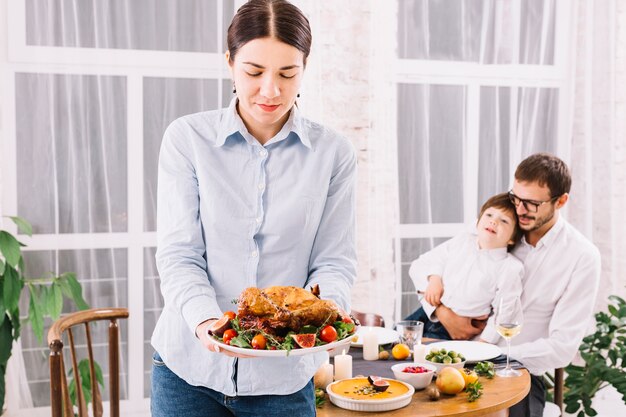 Mujer de pie con pollo al horno en placa