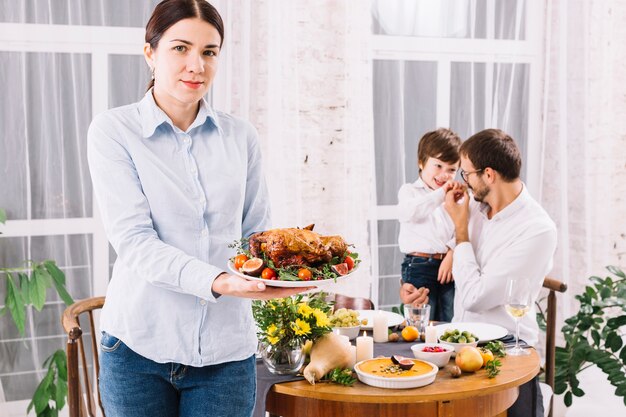 Mujer de pie con pollo al horno