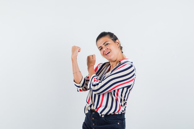 Mujer de pie en pose de lucha en camisa, falda y luciendo fuerte