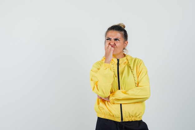 Mujer de pie en pose de pensamiento en traje deportivo y mirando triste, vista frontal.