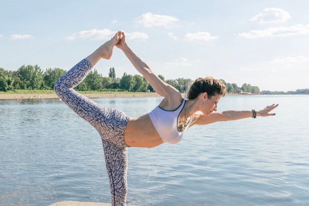 Mujer de pie en el río y haciendo yoga
