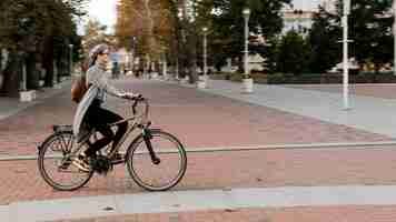 Foto gratuita mujer de pie sobre la bicicleta tiro largo