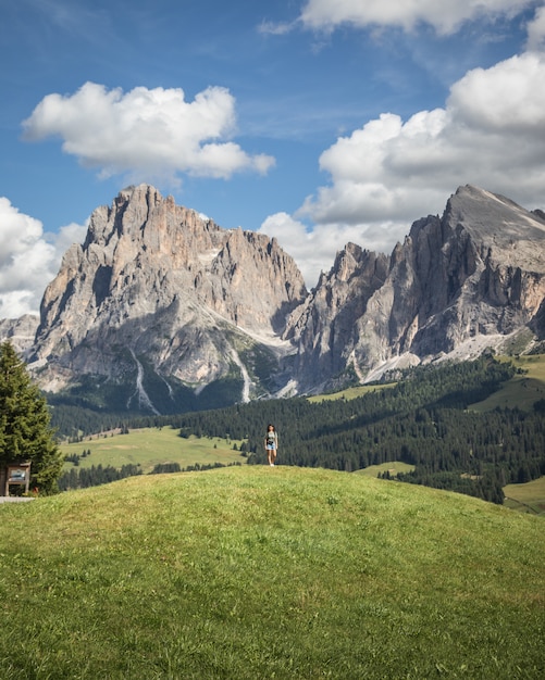 Mujer de pie sobre una colina con la montaña Plattkofel como telón de fondo en Compatsch Italia