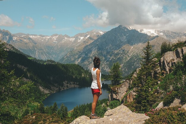 Mujer de pie sobre una roca en la cima de la montaña