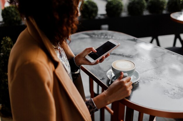 Mujer de piel oscura con peinado afro revisando sus noticias o mensajes a través de las redes sociales