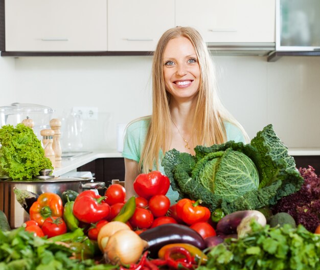 mujer con pila de verduras crudas en casa