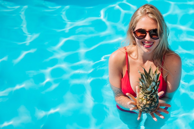 Foto gratuita mujer con piña en piscina con espacio de copia