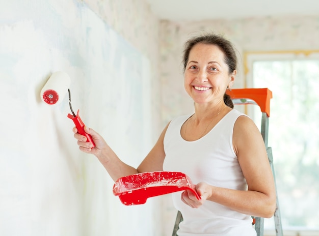 La mujer pinta la pared con el rodillo