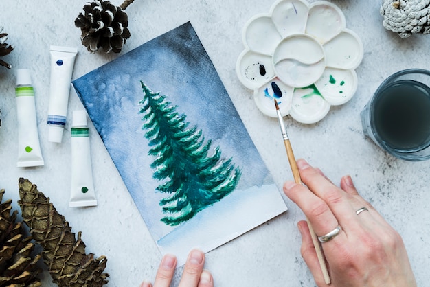 Mujer pintando el árbol de navidad con pincel