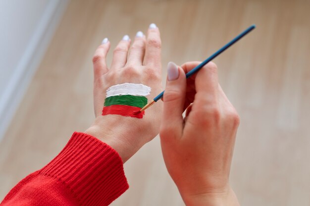 Mujer pintando la bandera búlgara en su mano