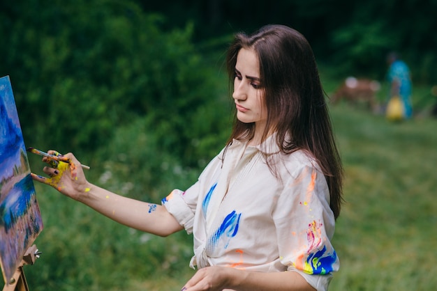 Mujer pintando un cuadro con un bosque de fondo