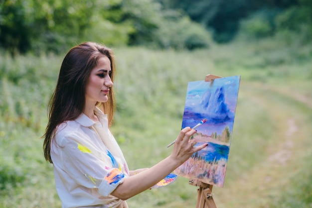 Mujer pintando un cuadro en el campo