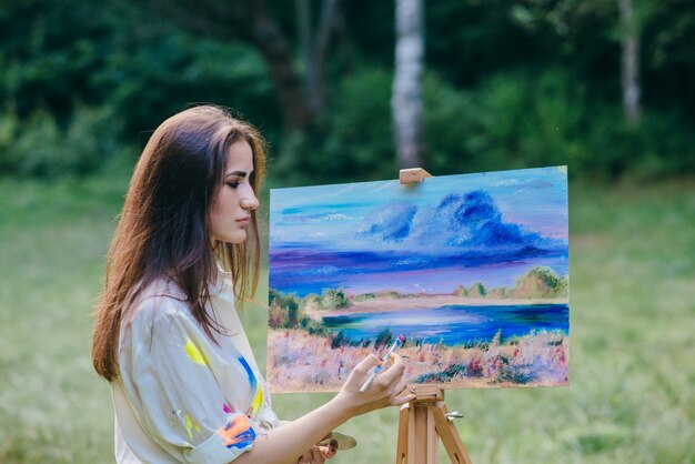 Mujer pintando un cuadro en el campo