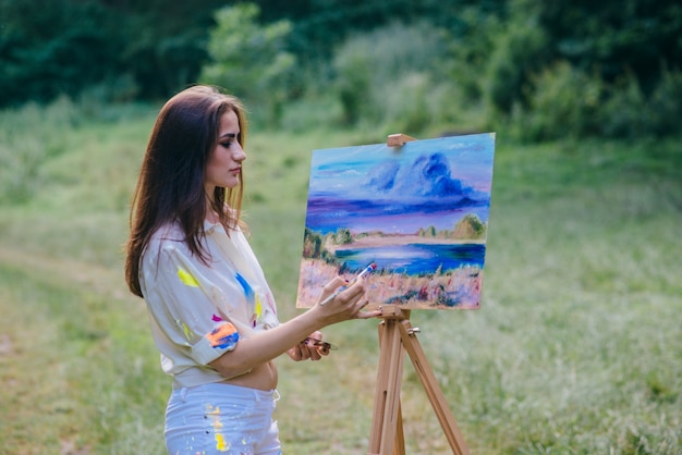 Mujer pintando un cuadro en el campo