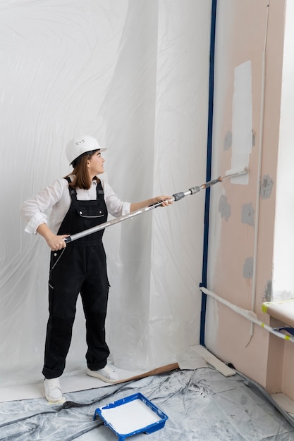 Mujer pintando la pared de la casa tiro completo