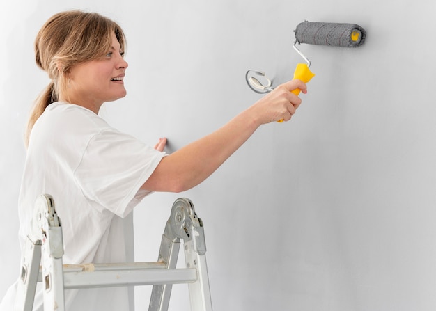 Mujer pintando la pared con rodillo