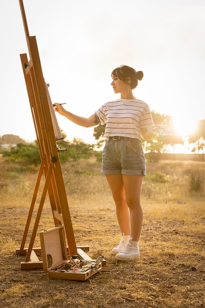 Foto gratuita mujer pintando sobre lienzo exterior en la naturaleza