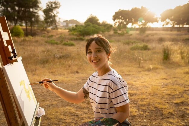 Mujer pintando sobre lienzo exterior en la naturaleza