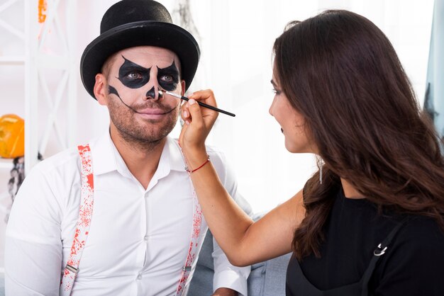 Mujer pintando a su hombre para halloween