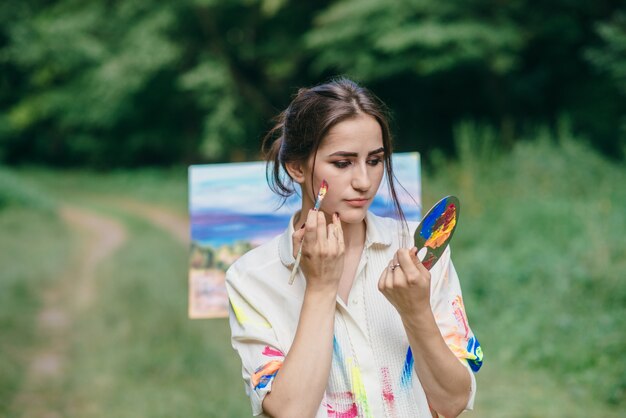 Mujer pintándose la cara con una brocha de pintura