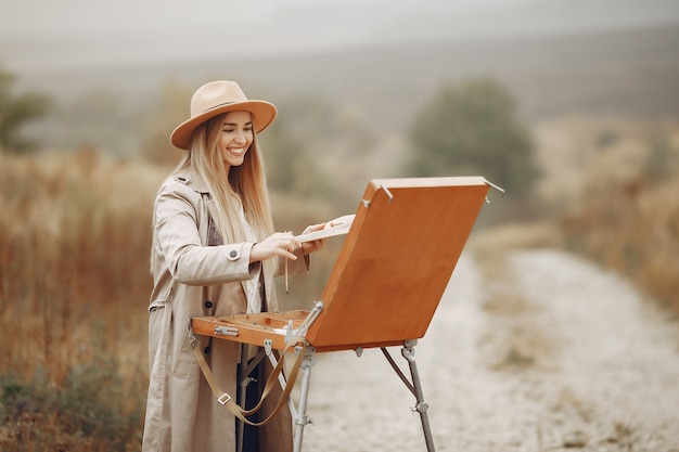 Mujer en una pintura de abrigo marrón en un campo
