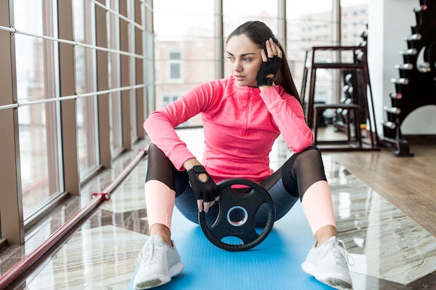 Foto gratuita mujer con placa de peso en el gimnasio